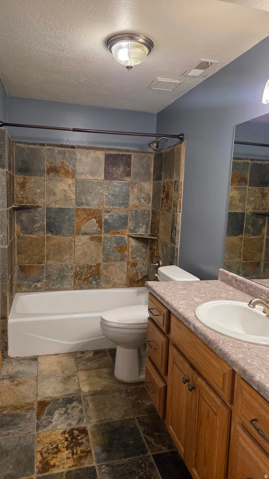 Bathroom #3 with stone tile flooring, vanity, shower / tub combination