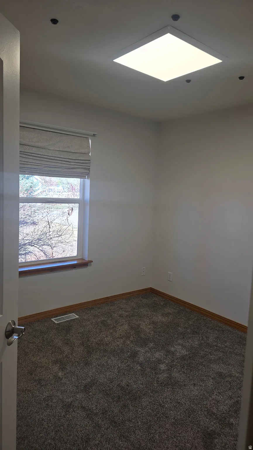 Unfurnished bedroom 1 featuring dark colored carpet and baseboards