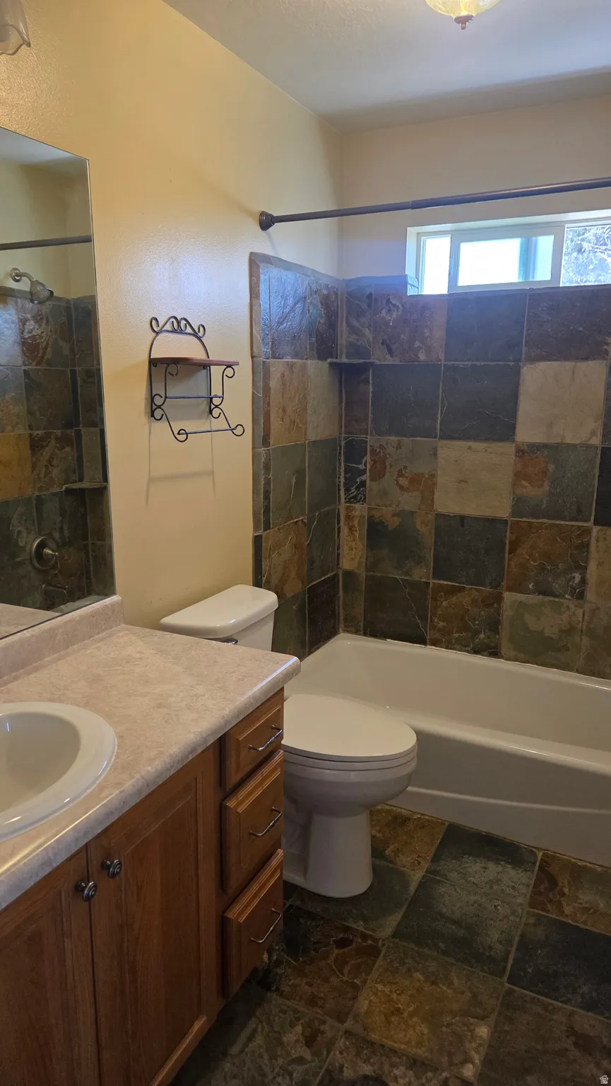 Full bathroom #1 featuring vanity, stone tile flooring, and shower / bath combination