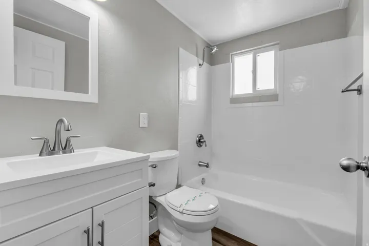 Full bathroom featuring vanity, bathtub / shower combination, a textured wall, and dark wood-style flooring