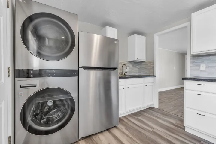 Laundry area with light wood-type flooring and stacked washer / drying machine