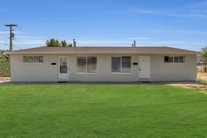 Single story home featuring concrete block siding, a front yard, and a shingled roof