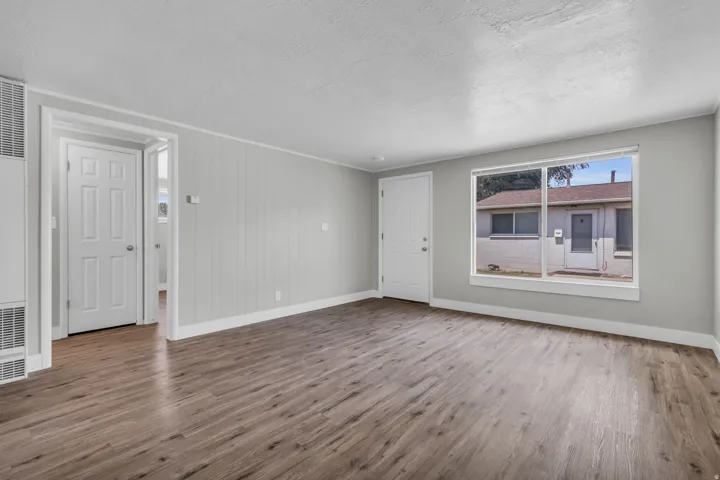 Unfurnished living room featuring dark wood-type flooring, a heating unit, and a textured ceiling