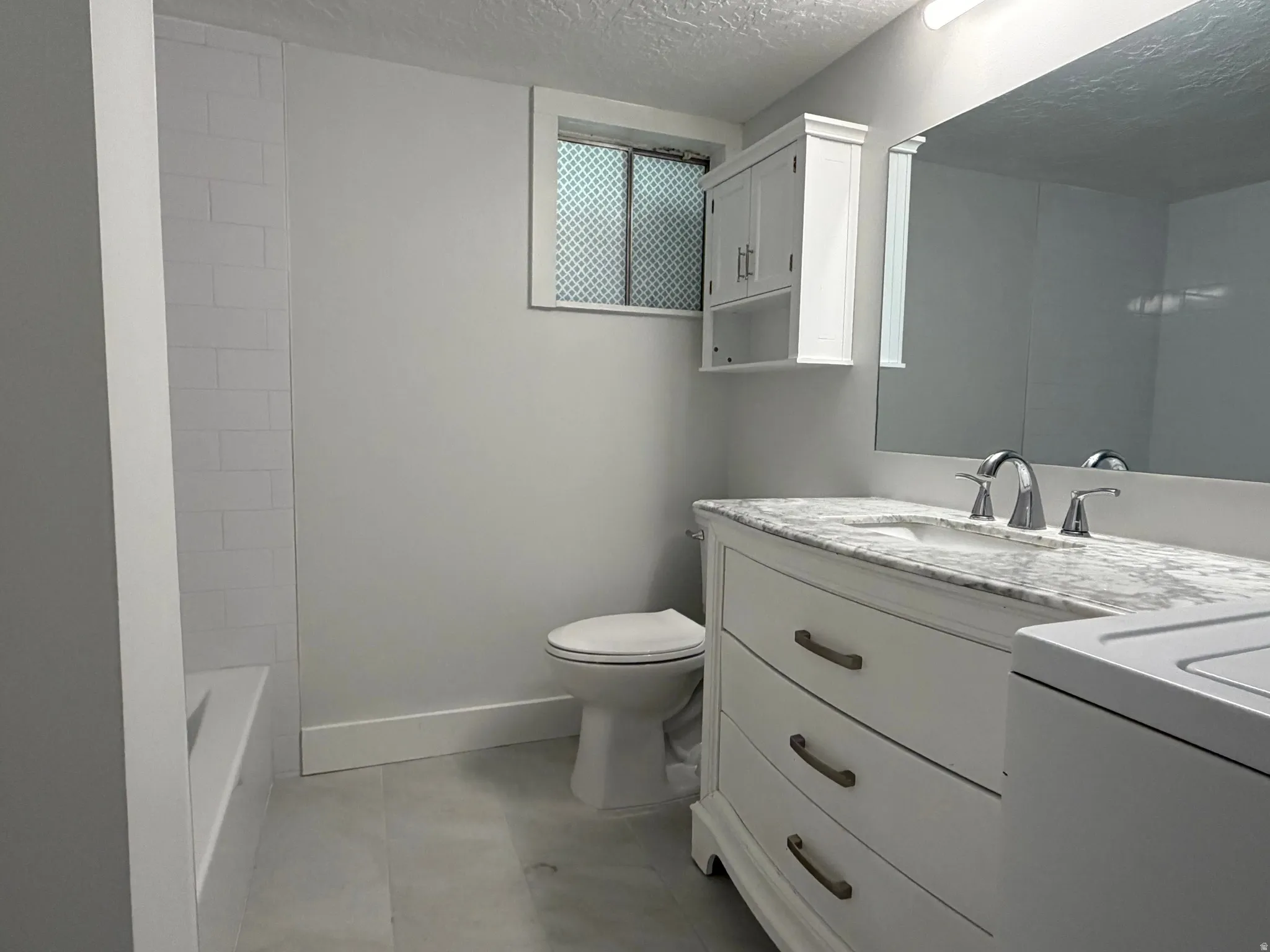 Full bath with vanity, a textured ceiling, and washer / clothes dryer