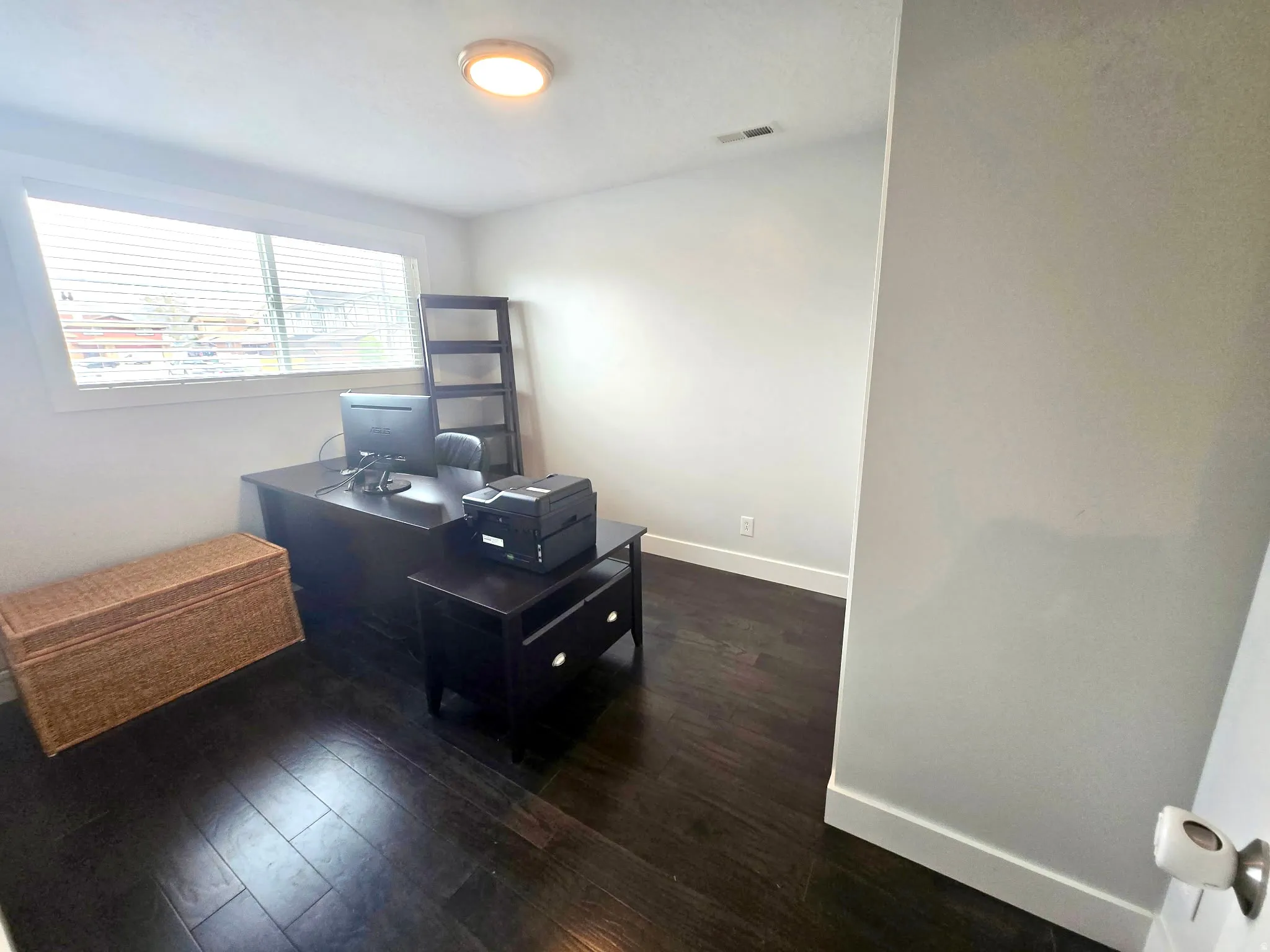 Office with dark wood-style floors and baseboards