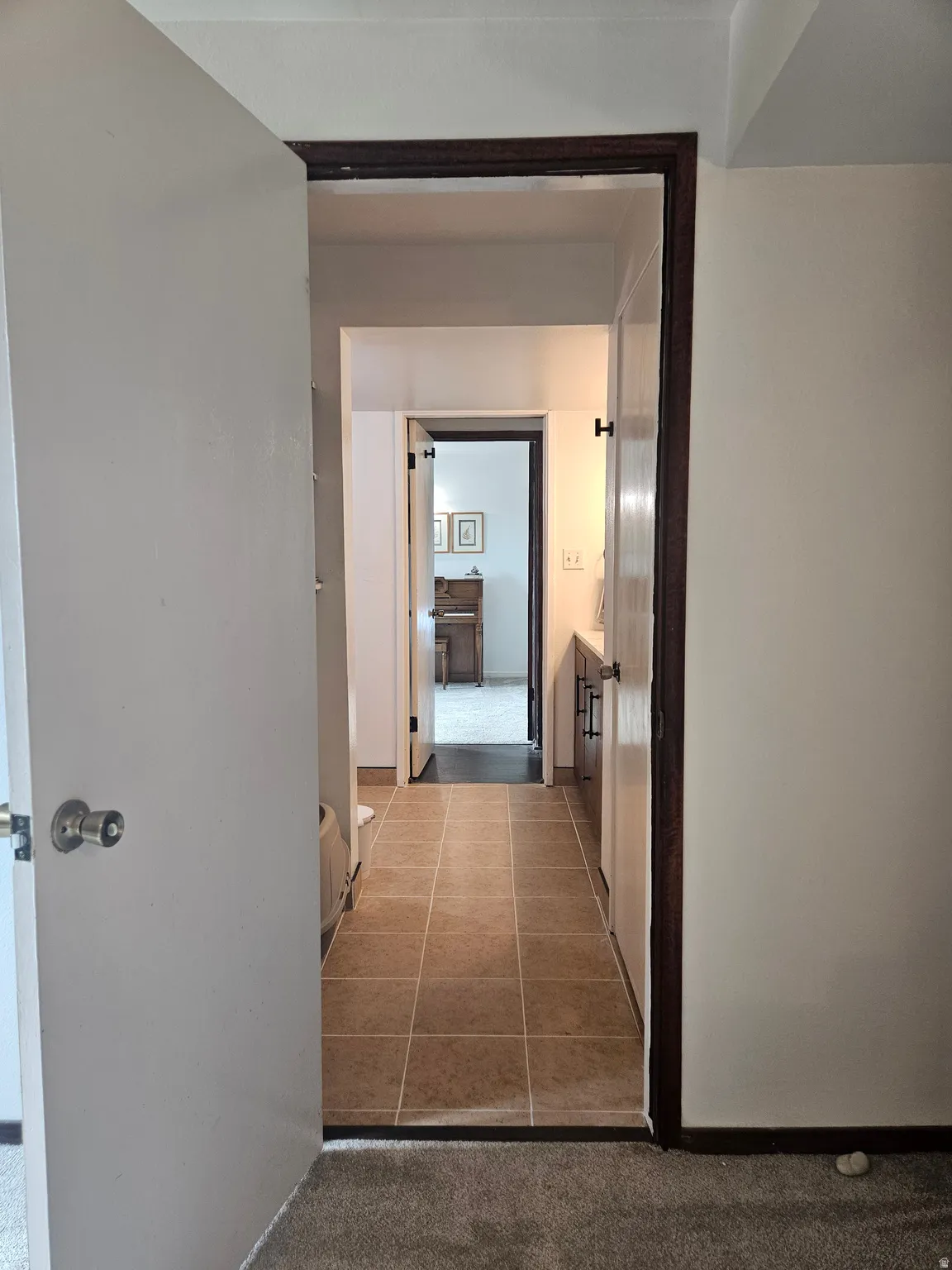 Corridor with light tile patterned floors and light carpet