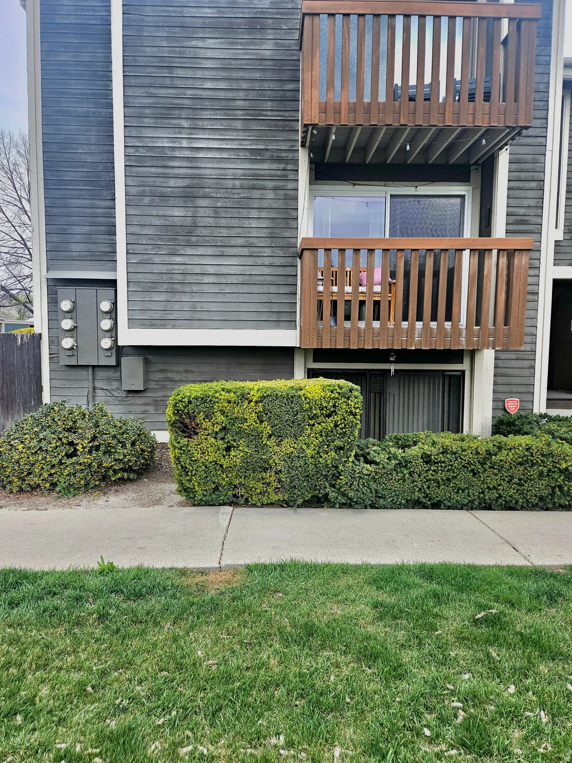 View of property exterior with a lawn and a balcony