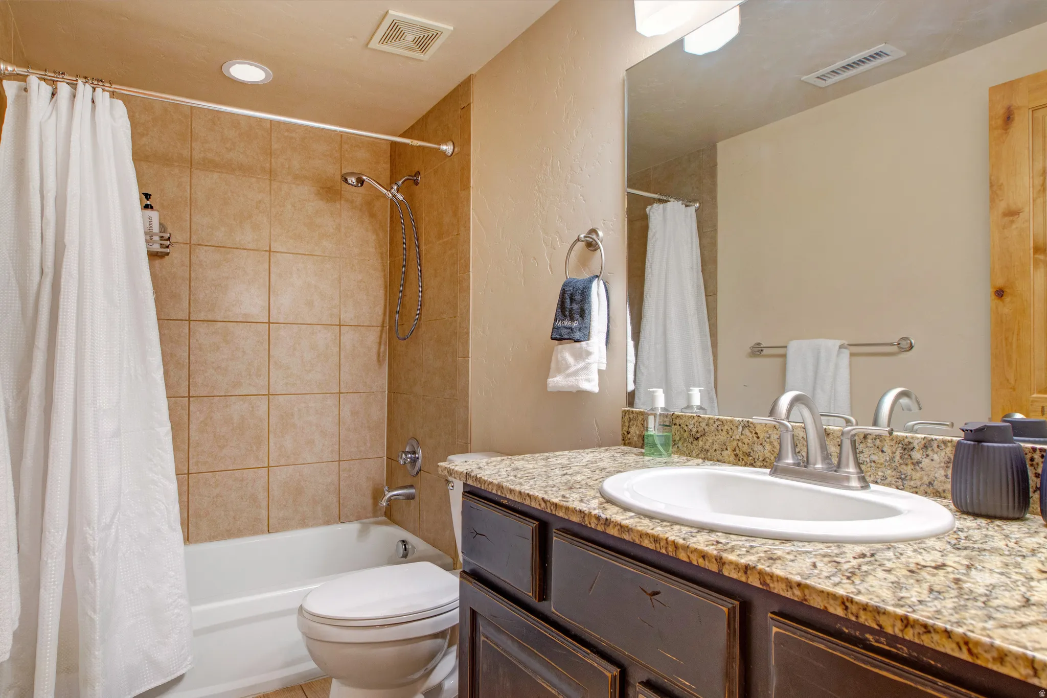 Bathroom featuring vanity, shower / bath combo with shower curtain, and a textured wall