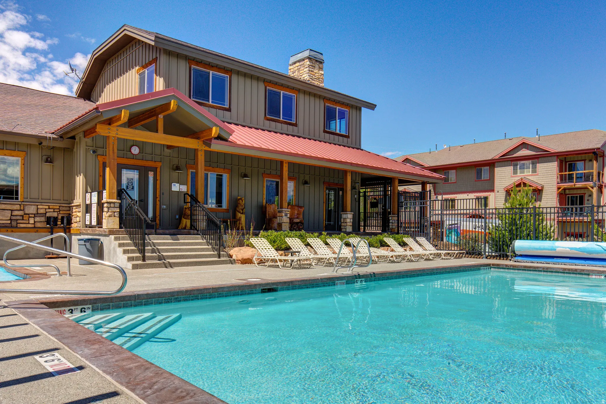 Rear view of property with board and batten siding, a community pool, a patio, and a metal roof