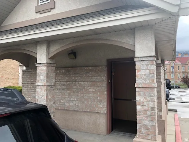 Entrance to property with stucco siding, elevator, and brick siding