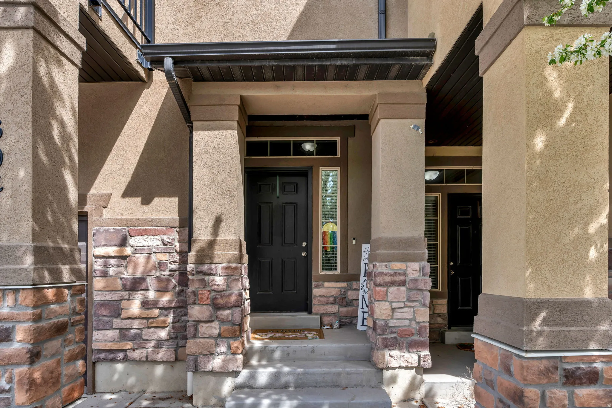 Property entrance with stucco siding, a porch, and stone siding