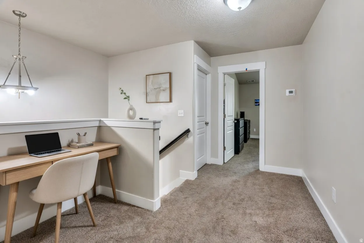 Home office with light carpet and a textured ceiling