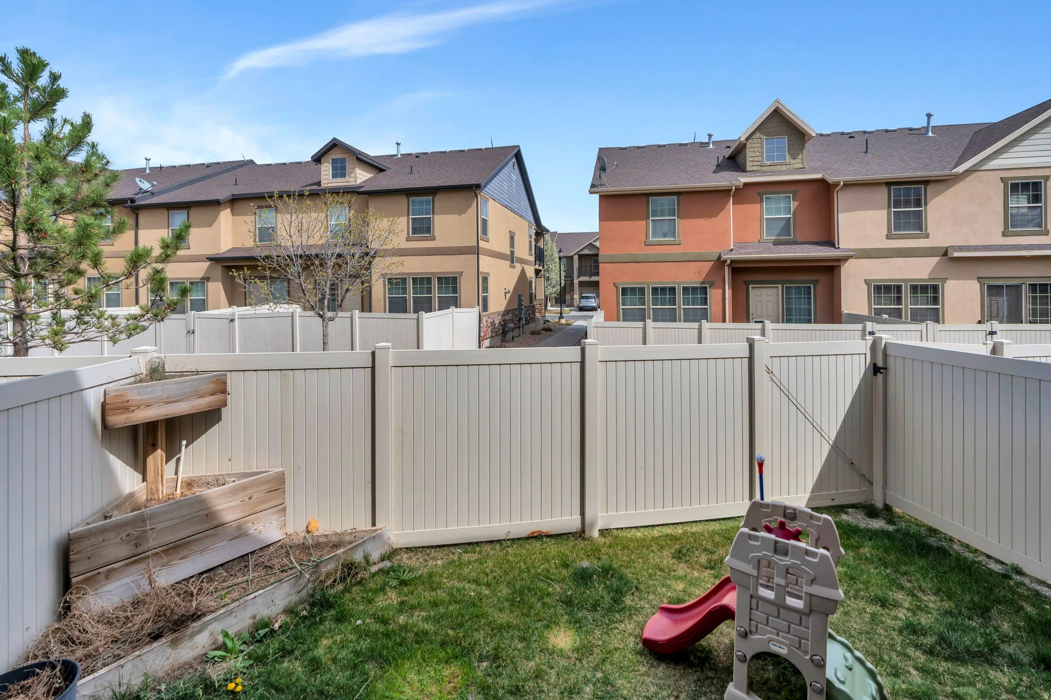 Fenced backyard featuring a residential view, a gate, and a garden