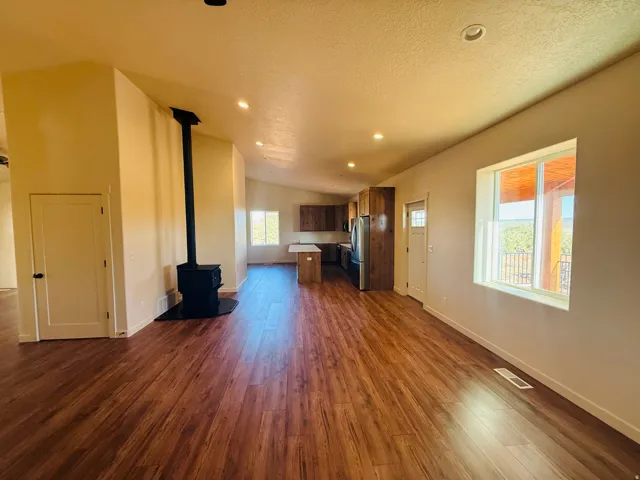 Unfurnished living room with a wood stove, dark wood-style floors, and recessed lighting