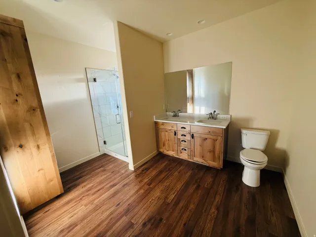 Master Full bath featuring double vanity, a stall shower, and dark wood finished floors