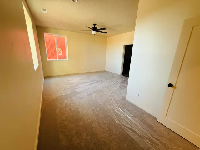 Master room with a textured ceiling, light colored carpet, and a ceiling fan