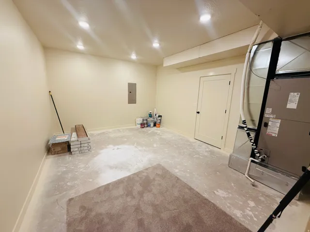 Utility room in basement featuring baseboards and electric panel