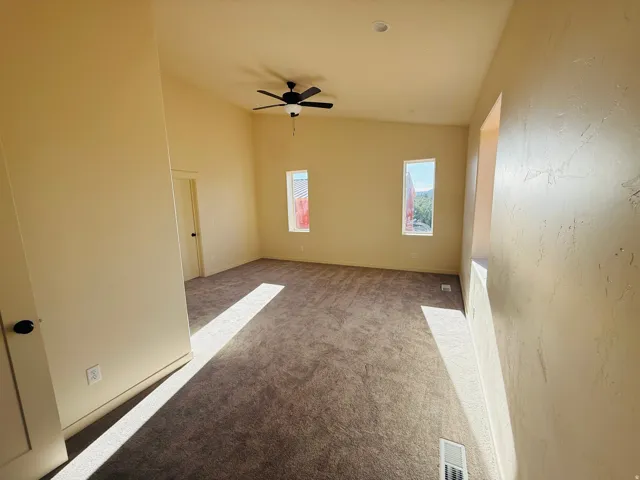 Master with light colored carpet, vaulted ceiling, and ceiling fan