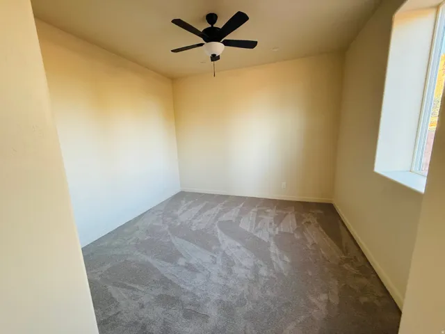 Spare room featuring carpet and ceiling fan