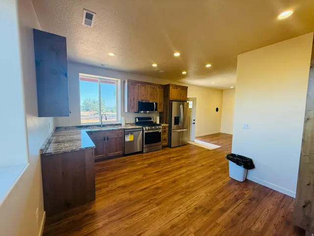 Kitchen featuring stainless steel appliances, dark stone counters, recessed lighting, and dark wood-style floors