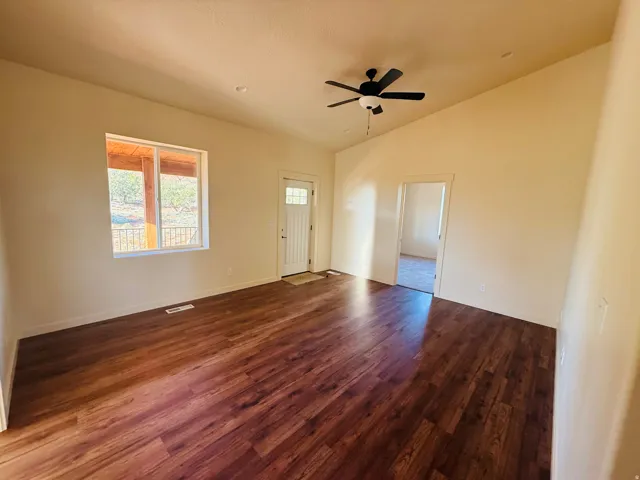 Spare room featuring dark wood-style floors, a ceiling fan, and lofted ceiling