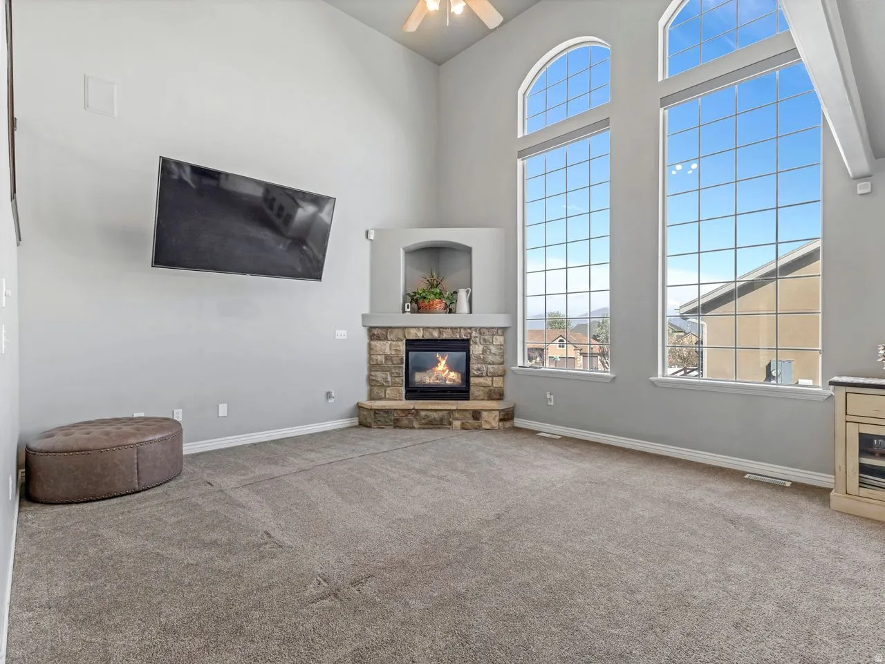 Living room with a high ceiling, carpet floors, a fireplace, and a ceiling fan
