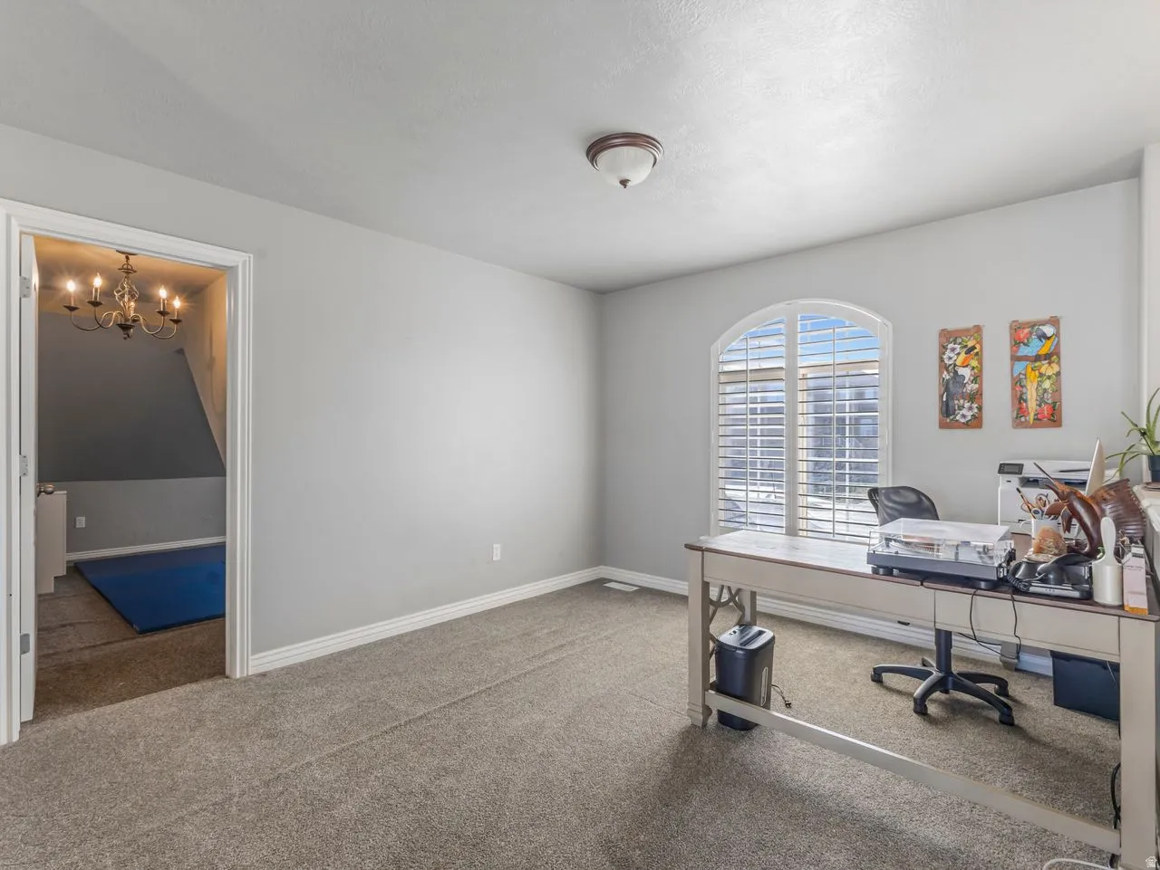 Carpeted office featuring baseboards and a chandelier