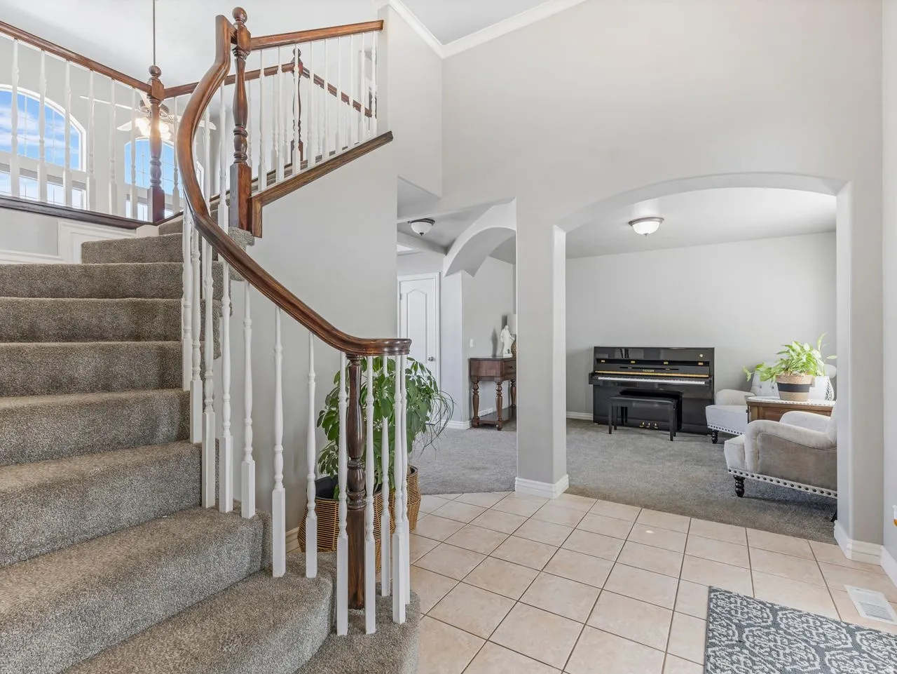 Foyer entrance featuring light colored carpet, arched walkways, light tile patterned floors, a high ceiling, and ornamental molding