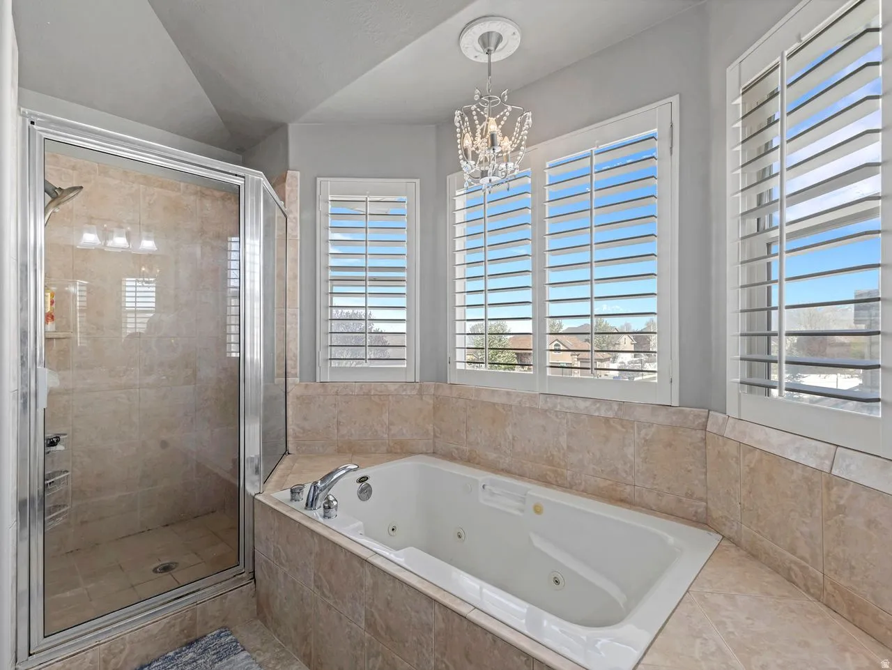 Full bathroom with a stall shower, a whirlpool tub, and a chandelier