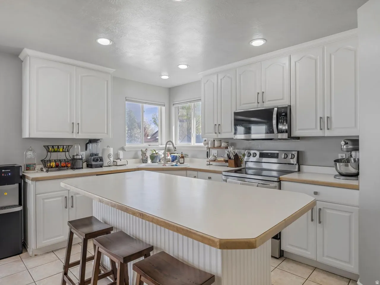 Kitchen featuring light countertops, stainless steel appliances, white cabinetry, and recessed lighting