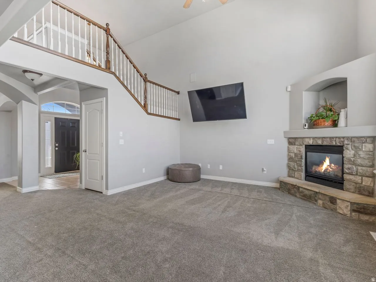 Unfurnished living room with arched walkways, a fireplace, a high ceiling, carpet floors, and a ceiling fan
