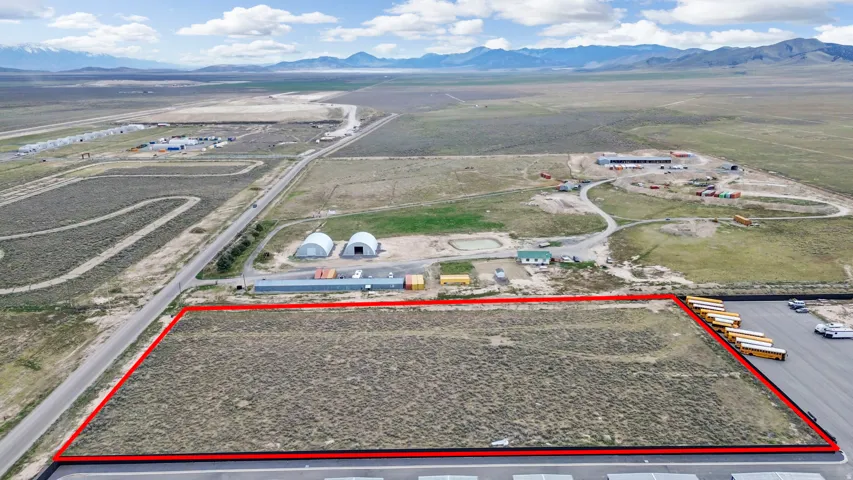 Aerial view of sparsely populated area featuring property boundaries highlighted and a mountainous background