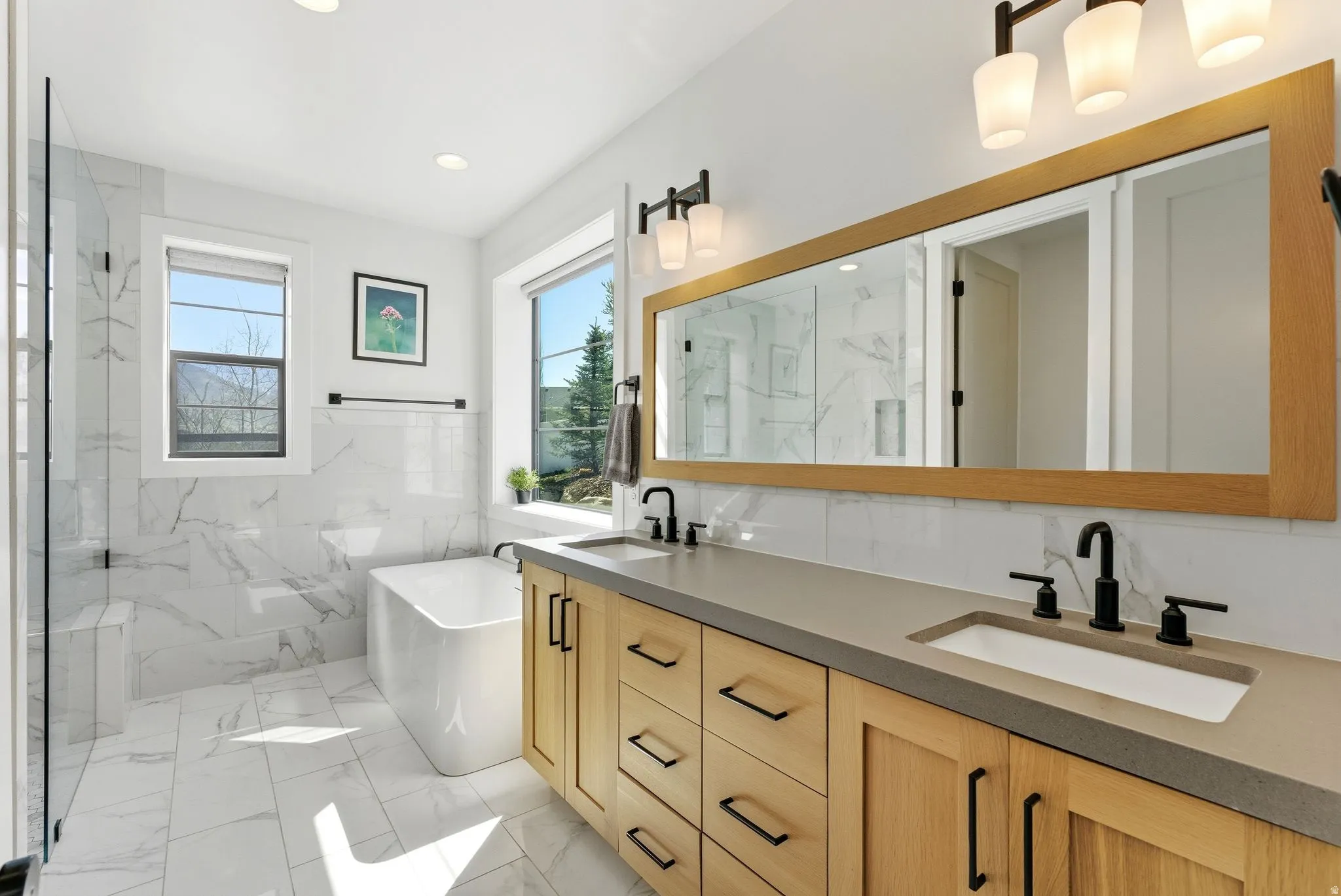Primary Bathroom with double vanity, a freestanding bath, a marble finish shower, light marble finish flooring, and recessed lighting
