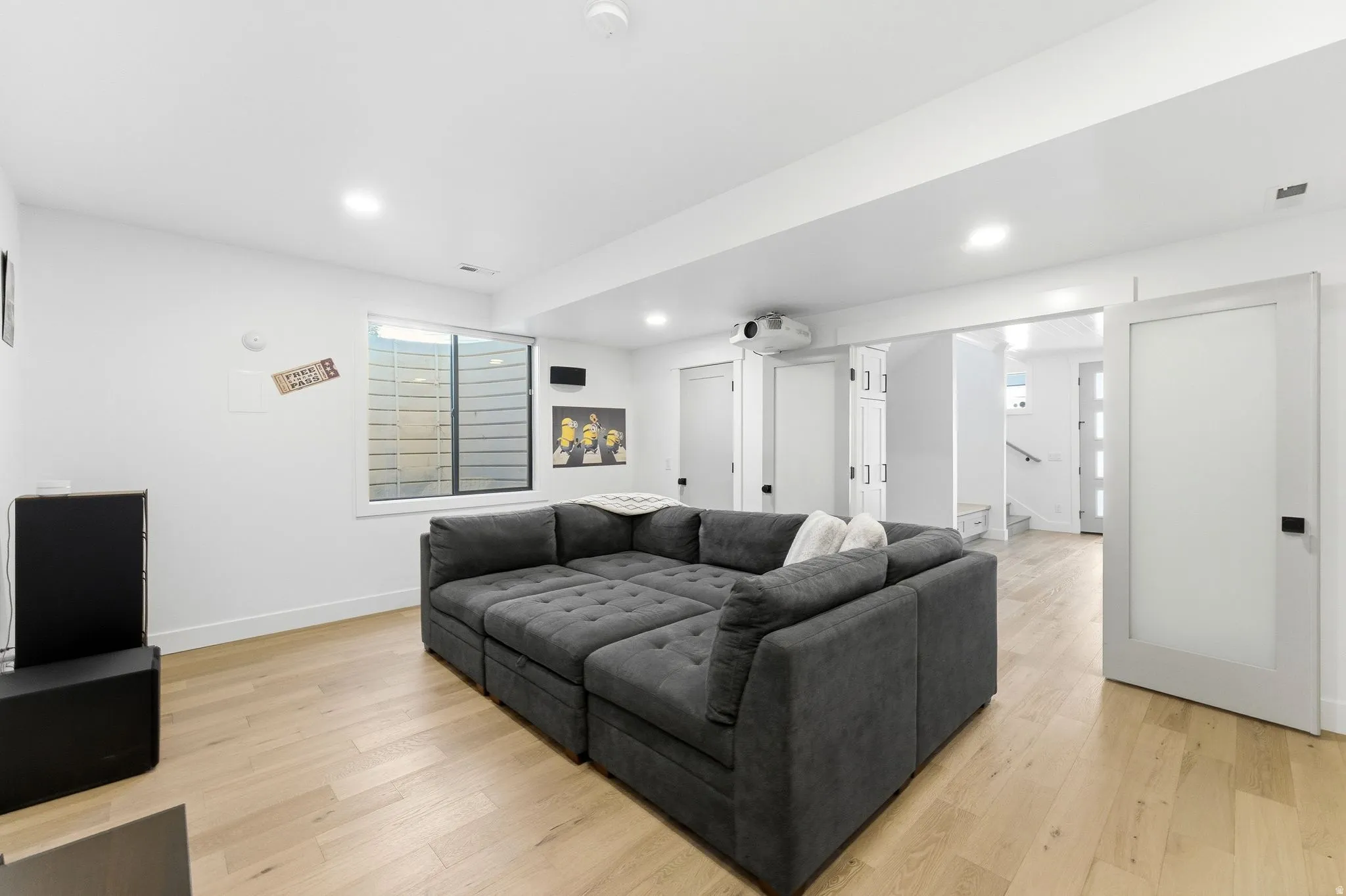 Living area with light wood finished floors and recessed lighting