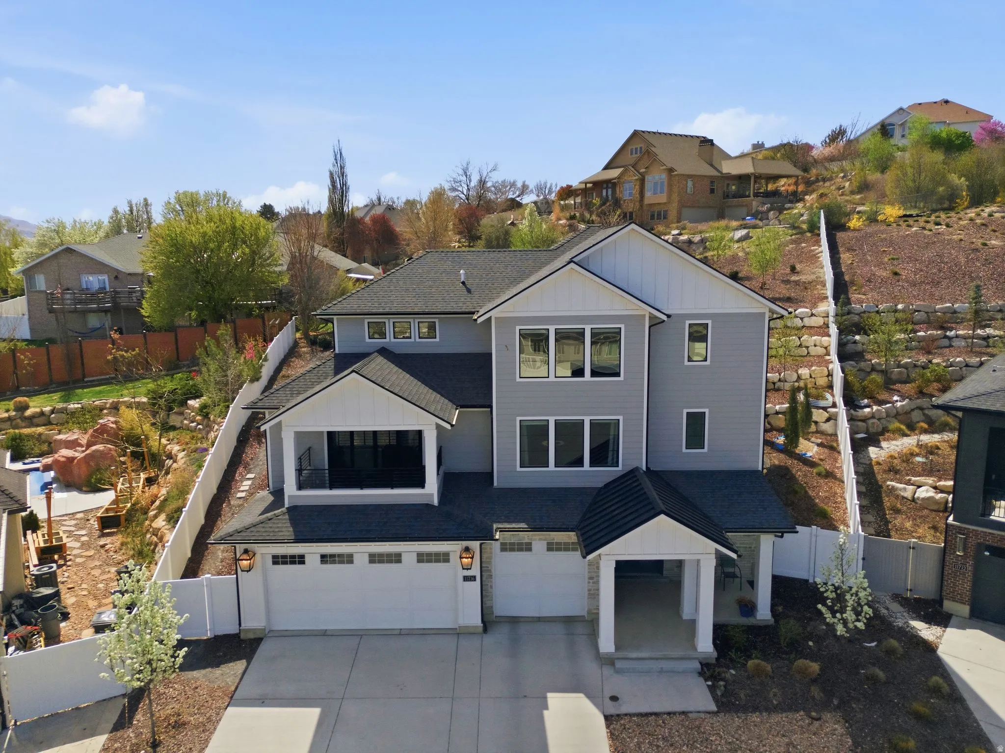 View of front of house featuring board and batten siding, an attached garage, driveway, and a residential view, low maintence yard