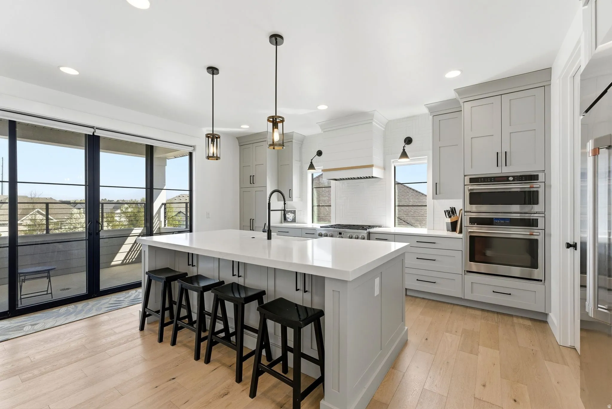 Kitchen with stainless steel appliances, light wood-style floors, gray cabinetry, a breakfast bar area, and healthy amount of natural light