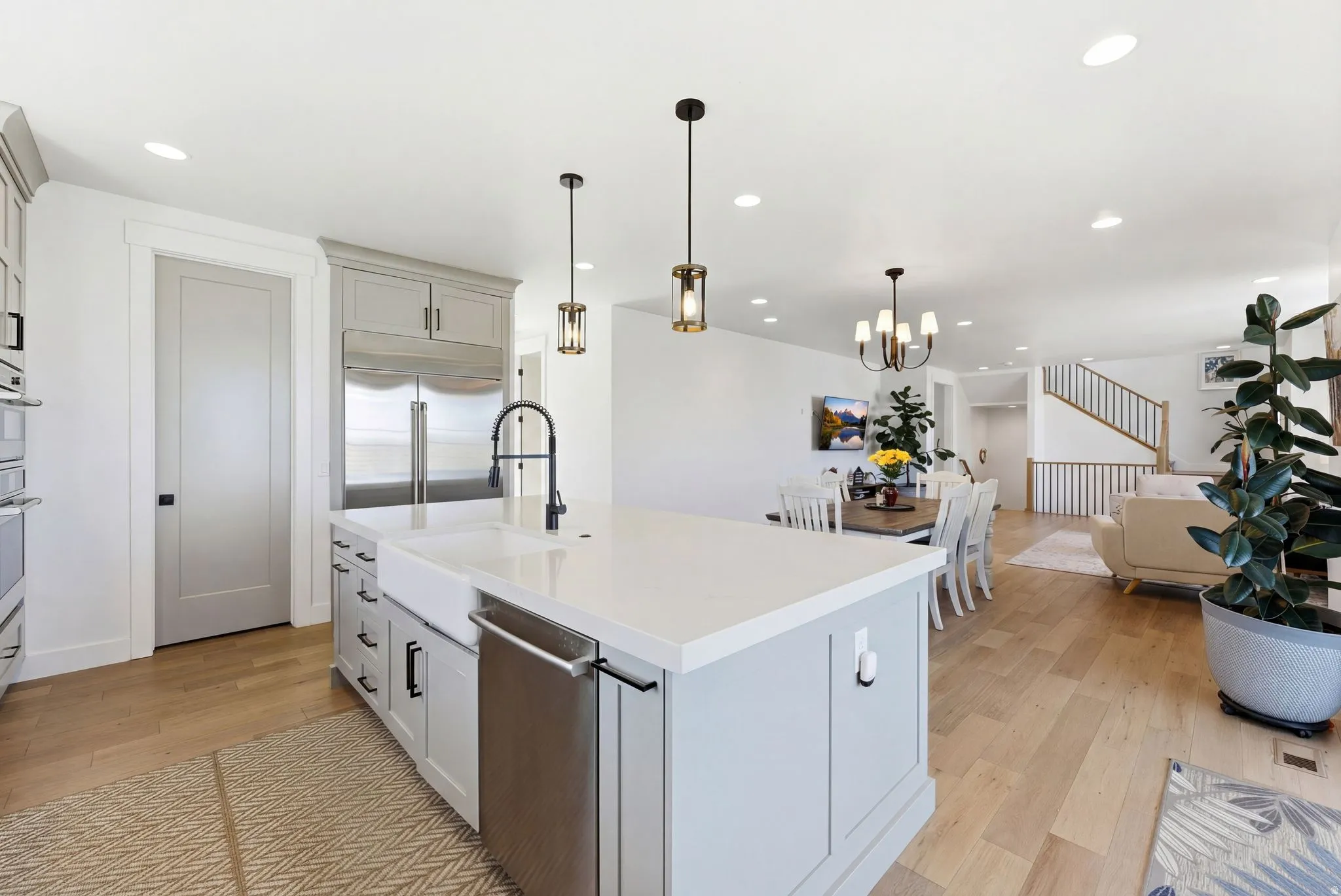 Kitchen with light wood-style floors, open floor plan, a center island with sink, stainless steel appliances, and pendant lighting