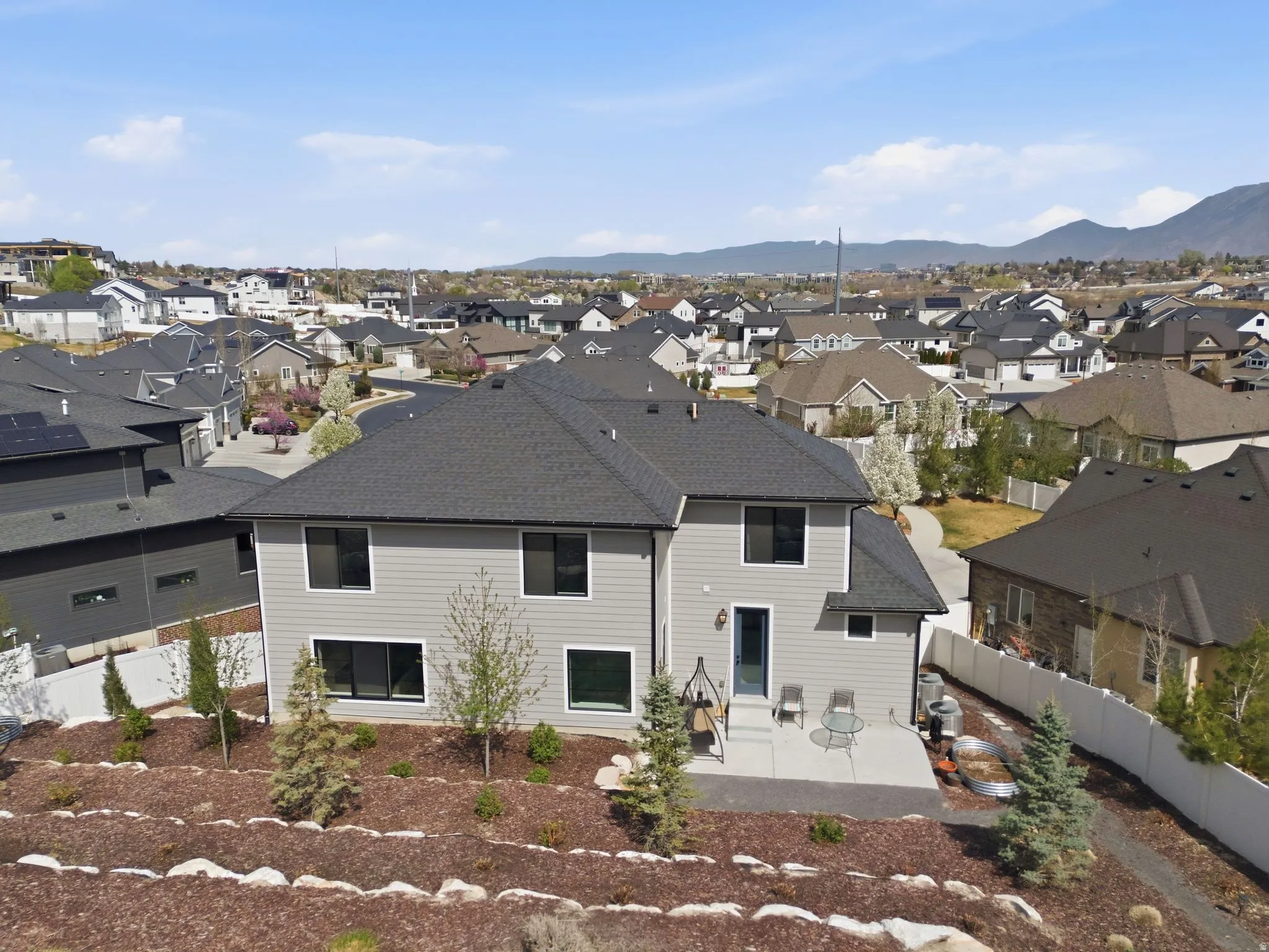 Rear view of property featuring a patio, a fenced backyard, roof with shingles, and a residential view