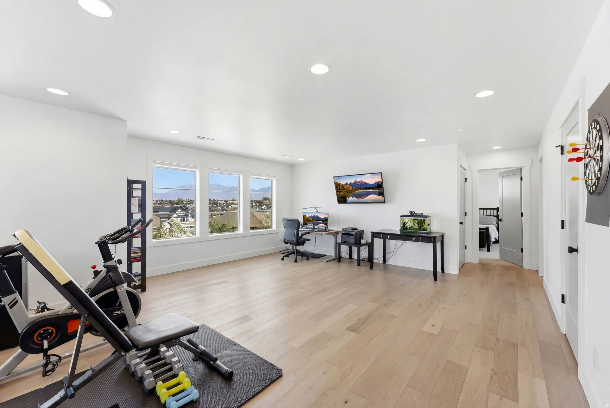 Exercise area with light wood-style floors and recessed lighting