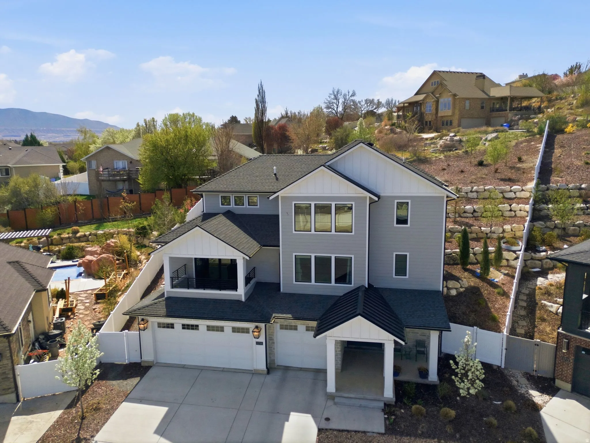 View of front facade with a gate, board and batten siding, an attached garage, a residential view, and driveway