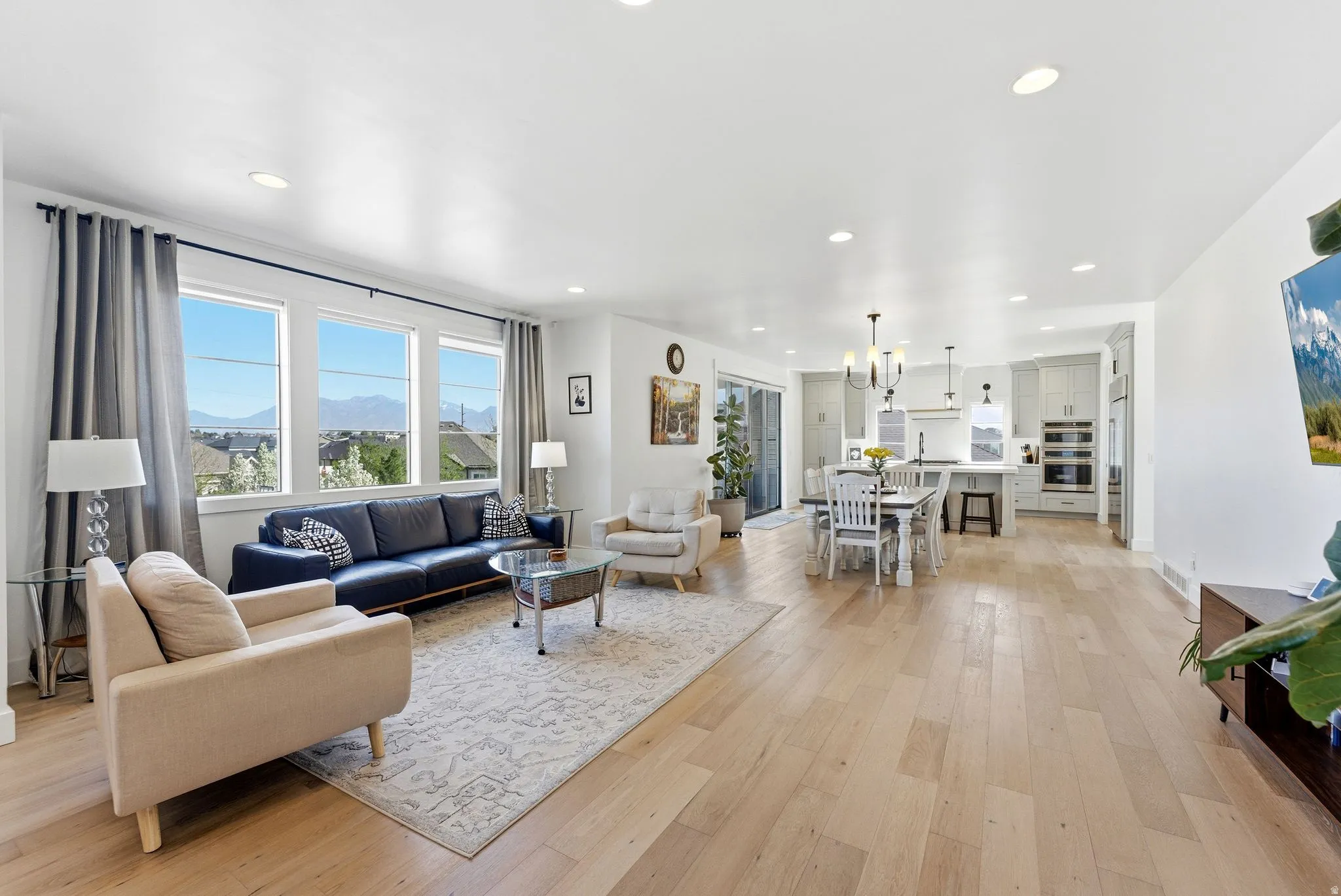Living room with a mountain view, light wood-type flooring, and hanging lights