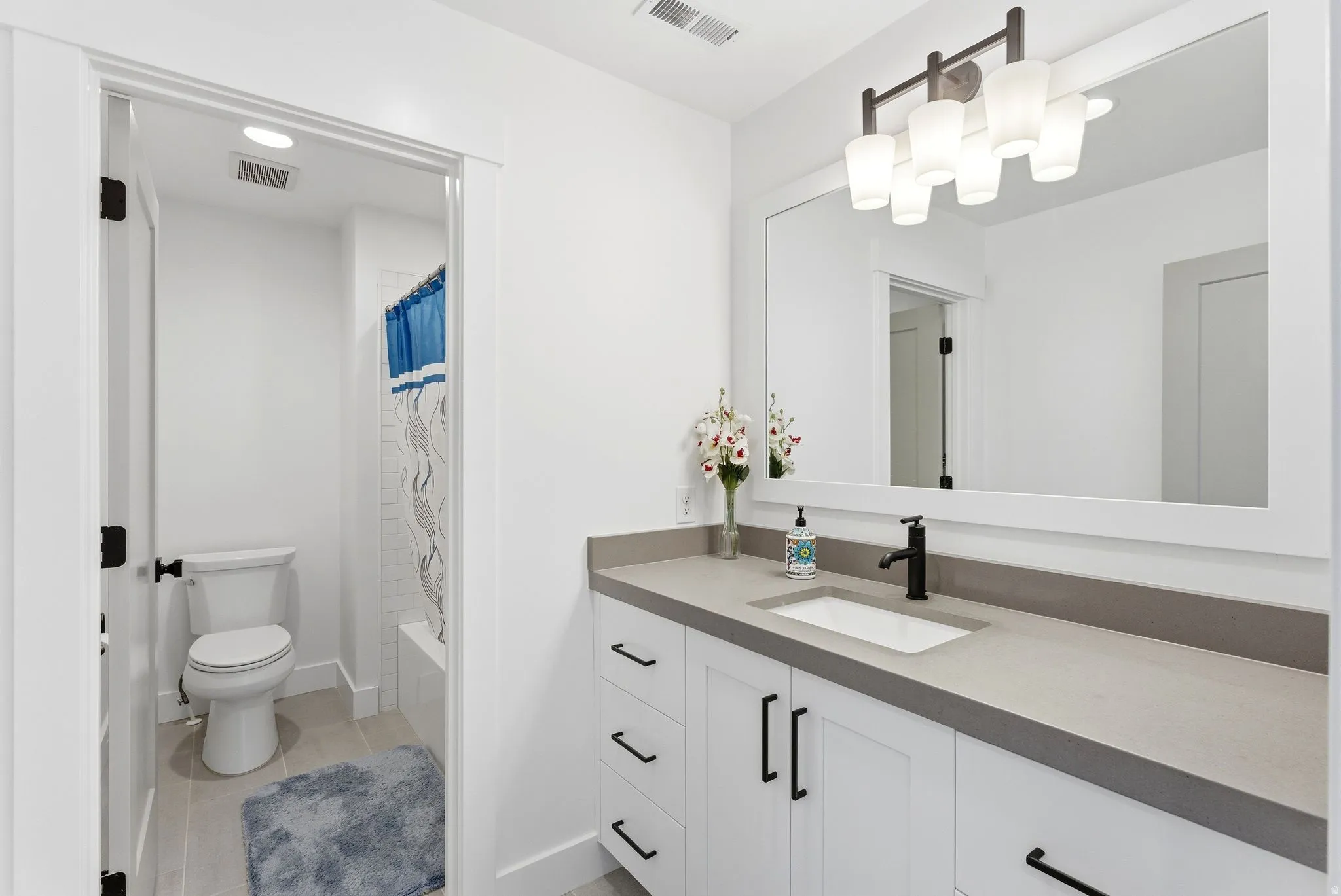 Bathroom with vanity, shower / tub combo, and light tile patterned floors
