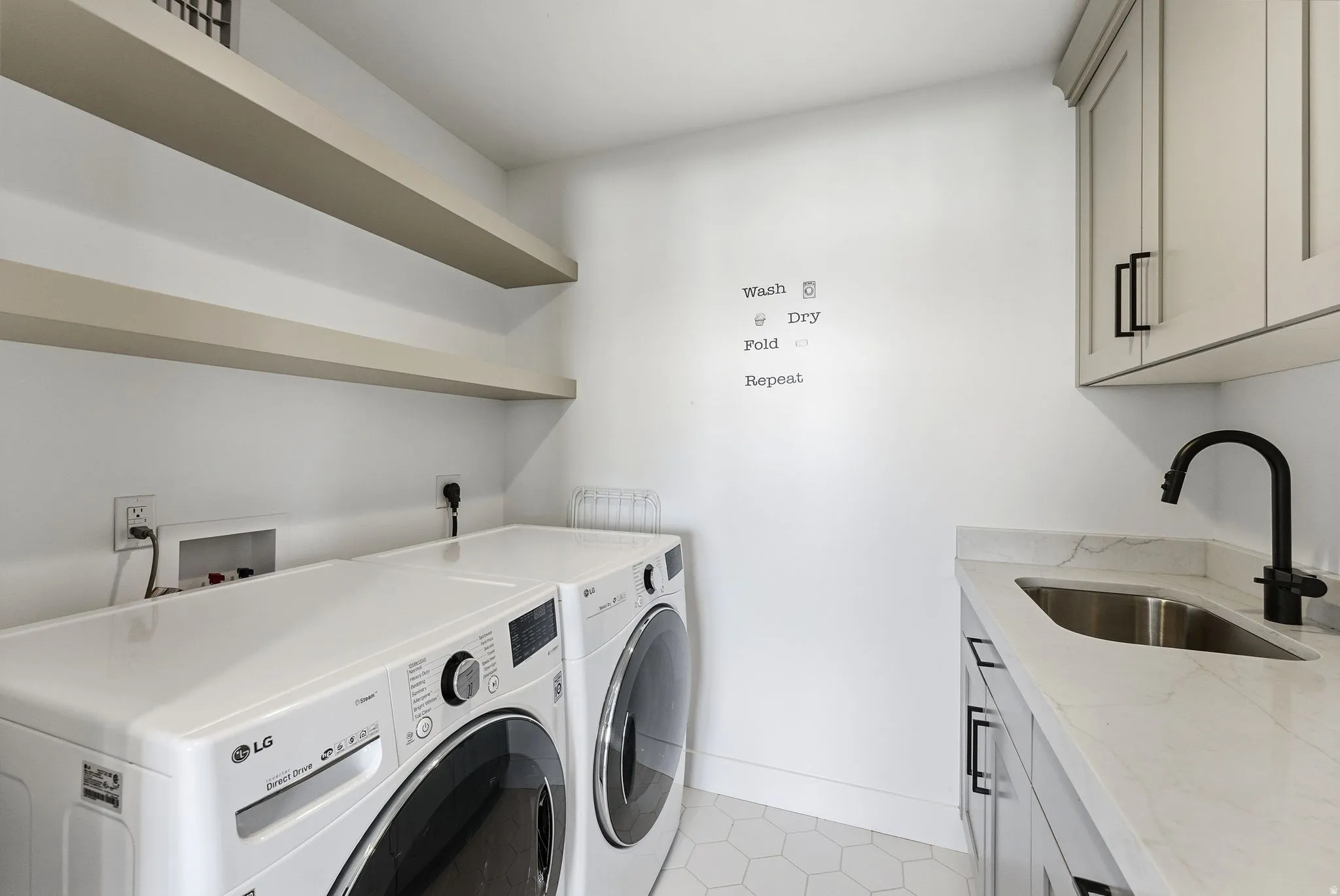 Laundry area featuring washing machine and clothes dryer, cabinet space, and light tile patterned floors