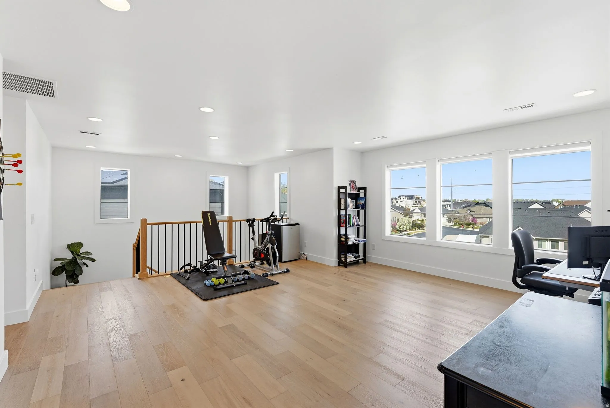 Exercise room with light wood-type flooring, recessed lighting, and healthy amount of natural light