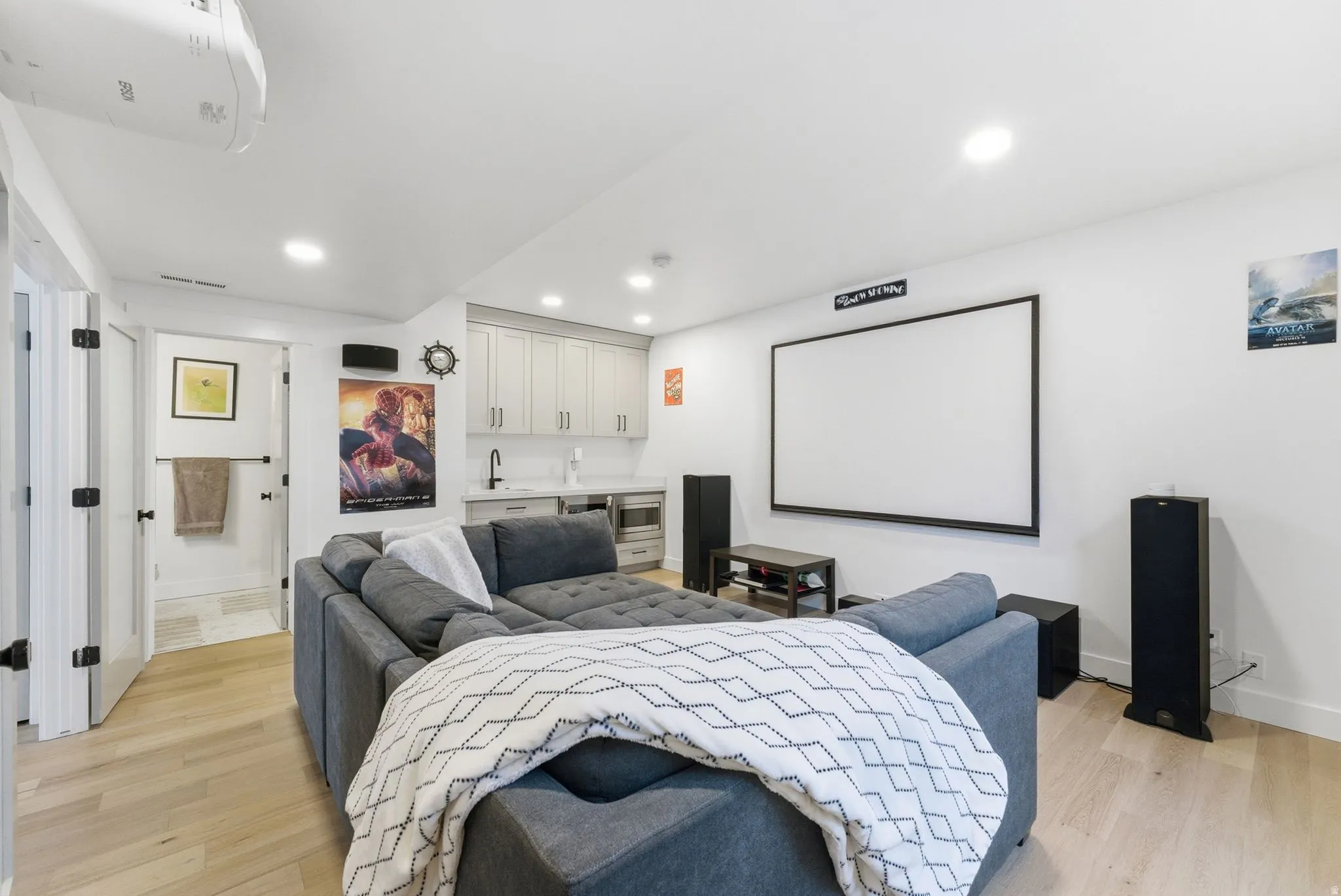 Home theater with bar with sink, light wood finished floors, and recessed lighting