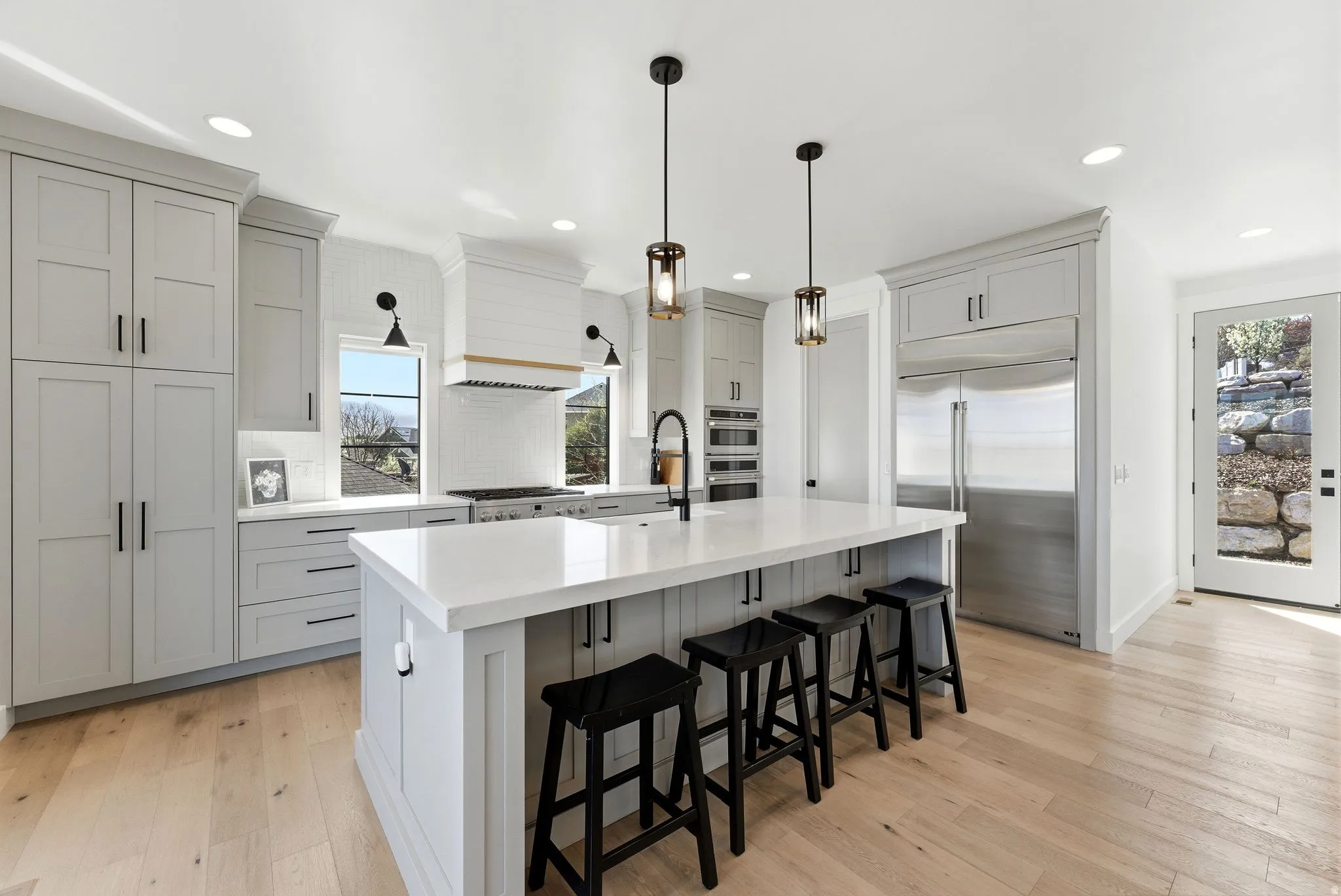 Kitchen with stainless steel appliances, a kitchen breakfast bar, backsplash, and light wood-style floors