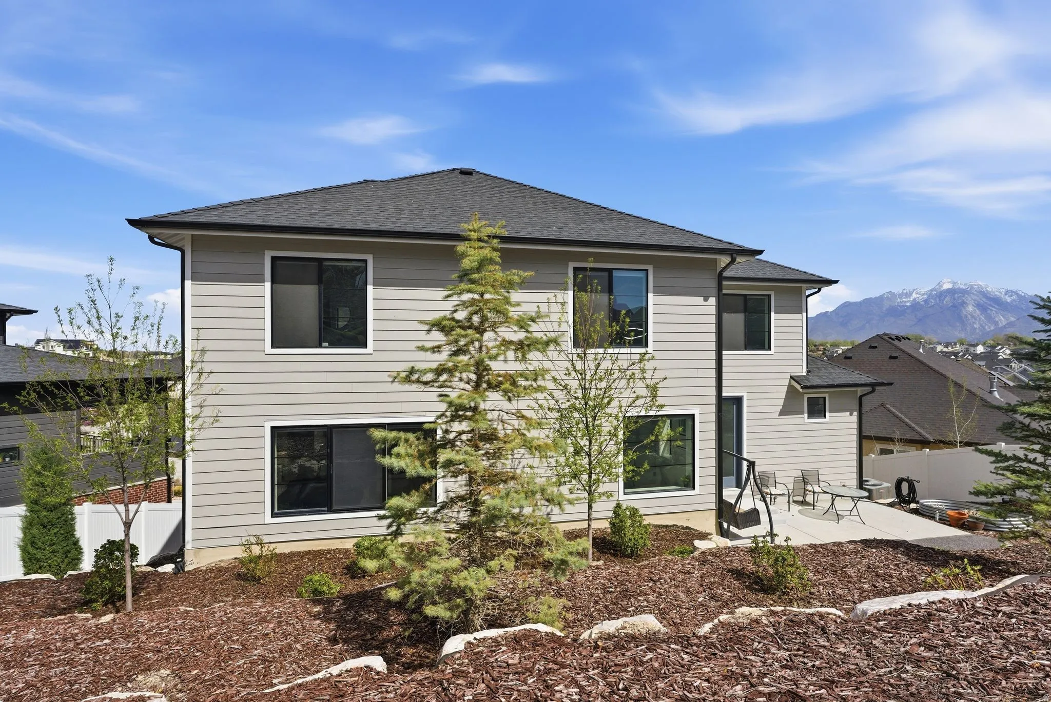 Back of house featuring a patio area, a mountain view, and roof with shingles