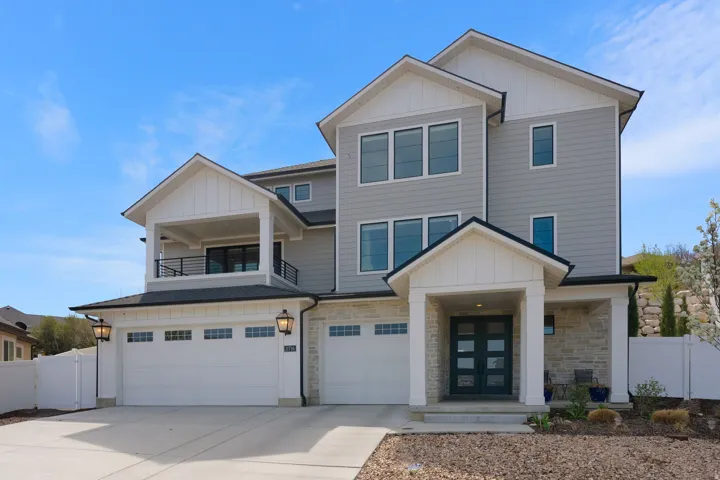 View of front of home with board and batten siding, stone siding, an attached garage, and concrete driveway
