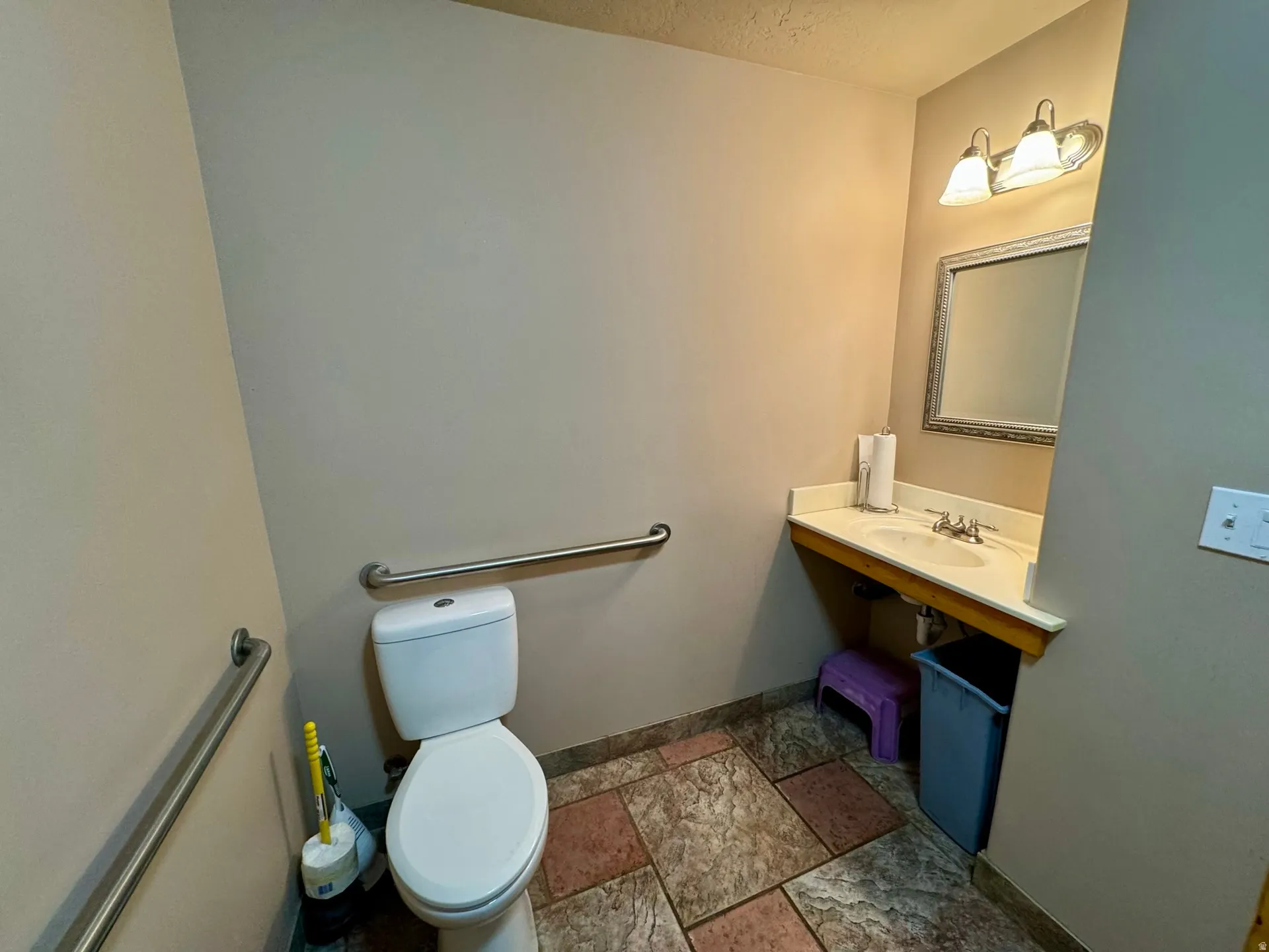 Half bathroom with stone tile flooring and vanity