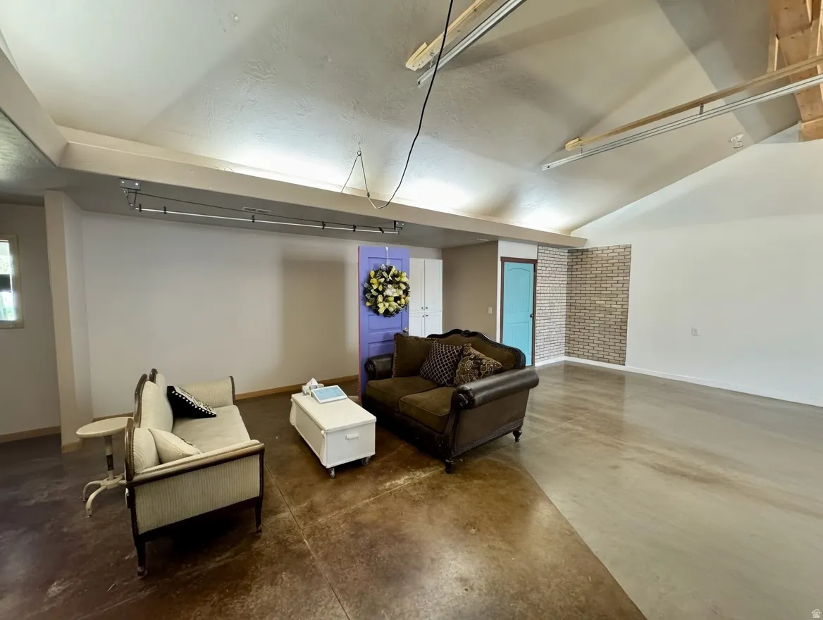 Sitting room featuring concrete floors and vaulted ceiling